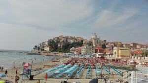 ein Strand mit einem Haufen Liegen und Sonnenschirmen in der Unterkunft Case Vacanze Borgo Marina IMPERIA in Imperia