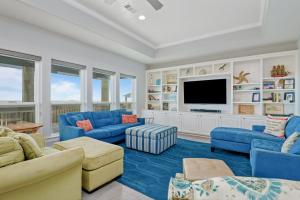 een woonkamer met blauwe meubels en een flatscreen-tv bij Just One More Day Home in Bolivar Beach +59 foto's