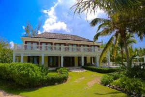 una gran casa blanca con una palmera en Alfred House & Cottage home, en Governorʼs Harbour