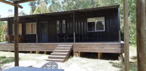 Una cabaña de madera con un porche y sillas delante. en Complejo Mirando el Cerro, en Punta Colorada