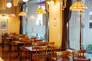 a dining room with tables and chairs and windows at Nest Hotel Matsuyama in Matsuyama