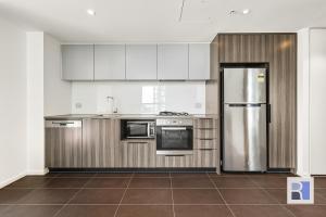 a kitchen with stainless steel appliances and white cabinets at REST COLLECTION Apartments on Collins Docklands in Melbourne