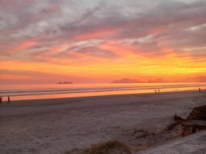 een zonsondergang op een strand met mensen die op het zand lopen bij Casa Aconchegante in Guarujá