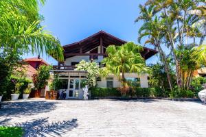 a house with palm trees in front of it at Suítes Jurerê Internacional in Florianópolis +43 photos