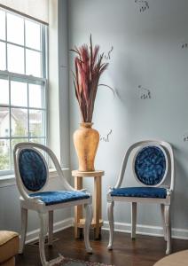 Dos sillas y un jarrón sobre una mesa en una habitación. en Azure Elephant Haven - 2 King Suites in Bayberry South, en Middletown