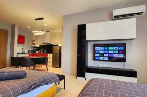 a room with a kitchen and a living room with a tv at Riverine Cozzy Resort RDA in Kuching