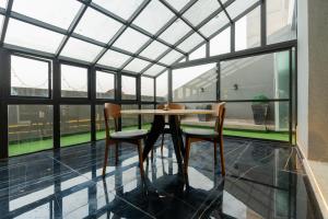 a table and two chairs in a room with windows at Gold Crest Prime Heights Executive Apartments-DHA Lahore in Lahore