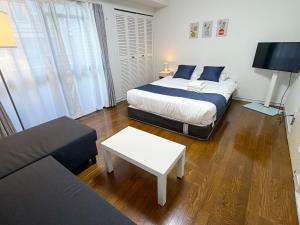 a bedroom with a bed and a living room with a couch at OUCHI HOTEL Tokaichi in Hiroshima