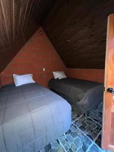 two beds in a room with a brick wall at AndeStay Hostel Colpapampa in Colcapampa +8 photos