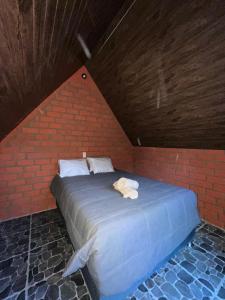 a bed in a brick room with towels on it at AndeStay Hostel Colpapampa in Colcapampa