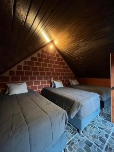 a room with two beds and a brick wall at AndeStay Hostel Colpapampa in Colcapampa