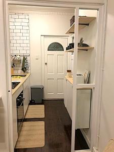 een kleine keuken met witte kasten en een deur bij Pet Friendly Acer Arena Accommodation in Sydney +1 foto