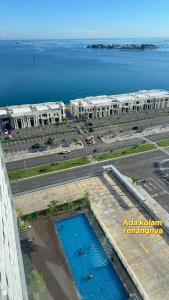 Una vista aérea de un edificio con piscina frente al agua. en Apartemen Delft Makassar, en Tanjungbunga