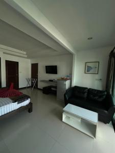 a living room with a black couch and a tv at The Seashore Kamala Service Apartment in Kamala Beach