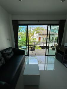 a living room with a couch and a large glass door at The Seashore Kamala Service Apartment in Kamala Beach
