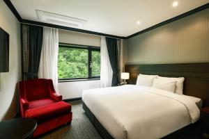 a hotel room with a bed and a red chair at KensingtonHotel Seorak in Sokcho