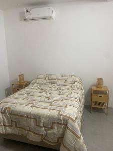 a bed with a comforter and a air conditioner on the wall at La Camelia in Juan L. Lacaze