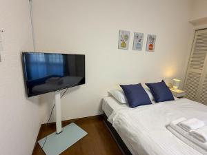 un soggiorno con una TV a schermo piatto su una parete di OUCHI HOTEL Tokaichi a Hiroshima