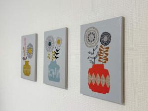 tre dipinti di vasi su una parete di OUCHI HOTEL Tokaichi a Hiroshima