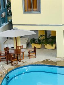 une piscine avec une table, des chaises et un parasol dans l'établissement Coral Sands - BriSta Stays, à Mombasa