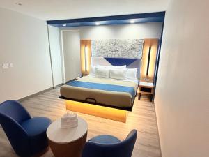 a bedroom with a bed and two chairs and a table at Crystal Inn - NorthWest - 290 in Houston