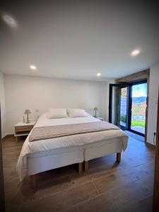 ein weißes Schlafzimmer mit einem großen Bett und einem Fenster in der Unterkunft Quinta dos Carvalhos in Cabana Maior