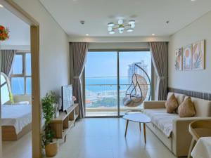 ViVi's Home - The Sóng Apartment Vũng Tàu في فنغ تاو: غرفة معيشة مع أريكة ونافذة كبيرة +255 صورة