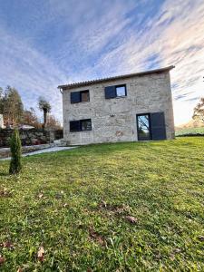 ein Steinhaus auf einem Grasfeld in der Unterkunft Quinta dos Carvalhos in Cabana Maior