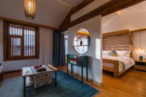 una camera con letto, specchio e tavolo di LiJiang Sunshine Garden Villa a Lijiang Altre 290 foto