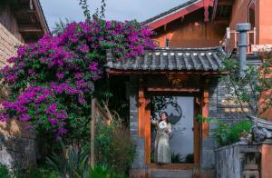 una foto di una sposa alla finestra con fiori viola di LiJiang Sunshine Garden Villa a Lijiang