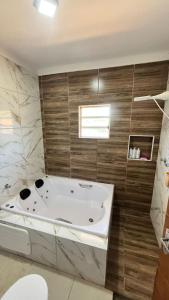 a bathroom with a bath tub and a sink at Recanto Maria de Souza in Caçapava