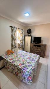 a bedroom with a bed with a flowered bedspread on it at Recanto Maria de Souza in Caçapava