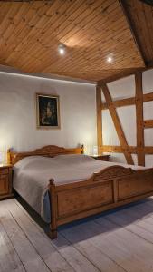 ein großes Holzbett in einem Zimmer mit Holzdecke in der Unterkunft Haus Anastasia in Stolberg i. Harz