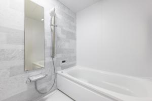 uma casa de banho branca com uma banheira e um espelho. em 暁の宿 em Koka mais 14 fotografias