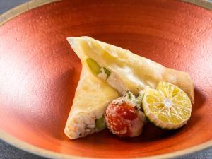 a orange plate with a piece of fish and a lemon at KAMENOI HOTEL Genkainada in Kitakyushu +80 photos