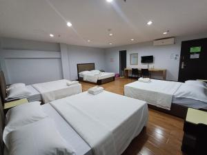 a hotel room with three beds and a flat screen tv at Asia Jem Hotel - Bacolod City in Bacolod