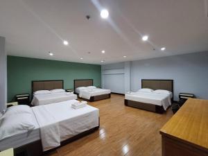 a room with three beds in a room with green walls at Asia Jem Hotel - Bacolod City in Bacolod