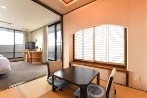 ein Wohnzimmer mit Tisch und ein Schlafzimmer in der Unterkunft サンシティーホテル山代 in Kaga