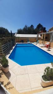 einen großen blauen Pool mit zwei Stühlen auf einer Terrasse in der Unterkunft Complejo Solares in Villa Carlos Paz