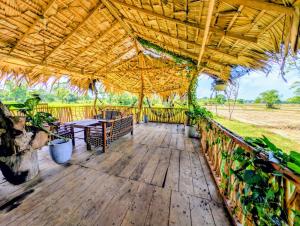 a wooden deck with a large straw umbrella at Thanamal-villa in Tanamalwila