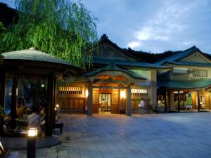 ein Gebäude, vor dem nachts Menschen sitzen in der Unterkunft サンシティーホテル山代 in Kaga