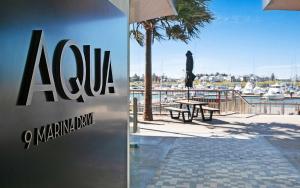 a sign for a marina with a man standing on a balcony at Aqua Cove - Marina Escape in Shellharbour