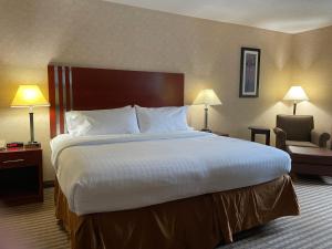 a hotel room with a large bed and a chair at Lynchburg Grand Estate by IHG in Lynchburg +10 photos