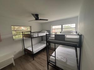 CG Miami House في ميامي: غرفة بها ثلاثة أسرة بطابقين ومروحة سقف