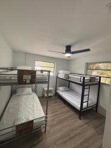 CG Miami House في ميامي: غرفة بها ثلاثة أسرة بطابقين ومروحة سقف