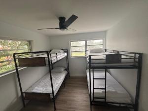 CG Miami House في ميامي: سريرين بطابقين في غرفة مع مروحة سقف