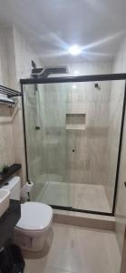 a bathroom with a glass shower and a toilet at Suites Novas in Cabo Frio