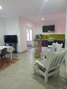 sala de estar con sillas blancas y cocina en Posada La Alemana, en Puerto Iguazú