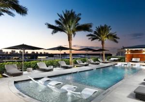 a pool with chairs and umbrellas and palm trees at Hanover River Oaks in Houston