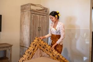 una mujer con un vestido sosteniendo un trozo de tela en Uma Shanty Homestay, en Karangasem